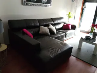 Sofá de piel negro , con patas de acero.