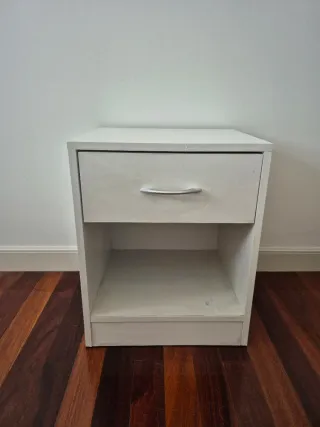Mesita de noche de madera color blanca.