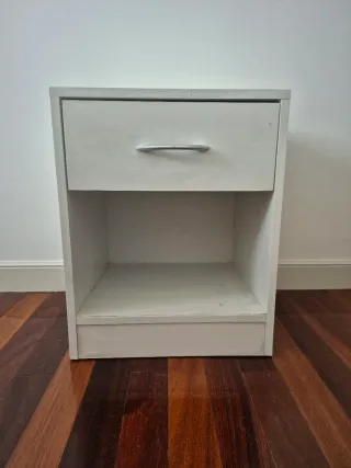 Mesita de noche de madera color blanca.