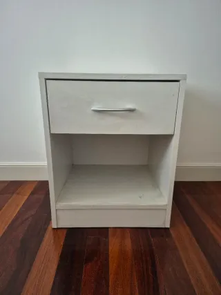 Mesita de noche de madera color blanca.