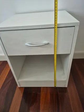 Mesita de noche de madera color blanca.