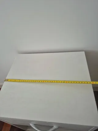 Mesita de noche de madera color blanca.