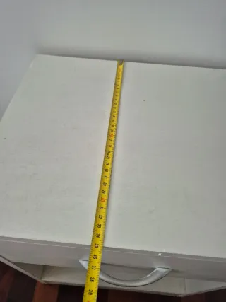 Mesita de noche de madera color blanca.