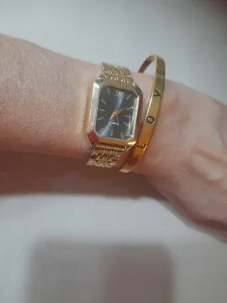 Reloj dorado de mujer y pulsera dorada.