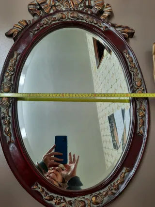 Espejo ovalado con marco tallado y detalle floral