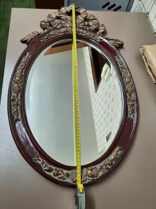 Espejo ovalado con marco tallado y detalle floral