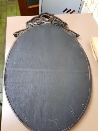 Espejo ovalado con marco tallado y detalle floral