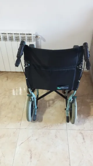 Silla de ruedas plegable azul con frenos.