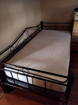 Cama de forja negra y colchón.