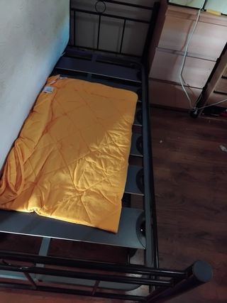 Cama de forja negra y colchón.