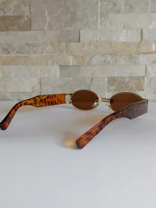 Occhiali da sole ovali con montatura dorata