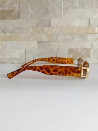 Occhiali da sole ovali con montatura dorata