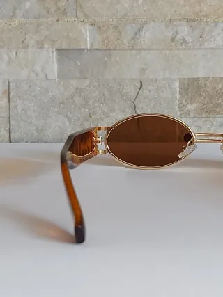 Occhiali da sole ovali con montatura dorata