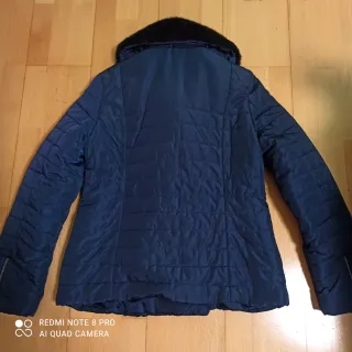 Chaqueta acolchada azul con cuello de pelo negro.