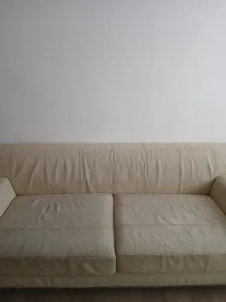 Sofá de piel beige con reposapiés.