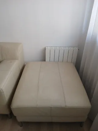 Sofá de piel beige con reposapiés.