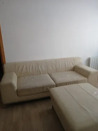 Sofá de piel beige con reposapiés.