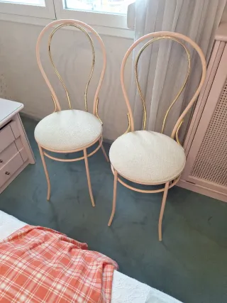 Sillas de color rosa y dorado.