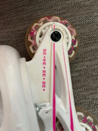 Patines rosa y blanco de tres ruedas, lineal.