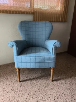 Sillón azul de tela con patas de madera