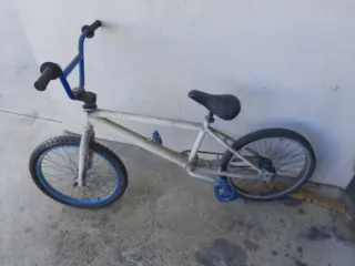 Bicicleta BMX blanca y azul cubiertas en mal estad
