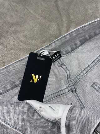 Pantalones tejanos anchos grises rasgados.