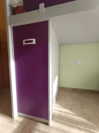 Cama litera con armario, escaleras y mesita.