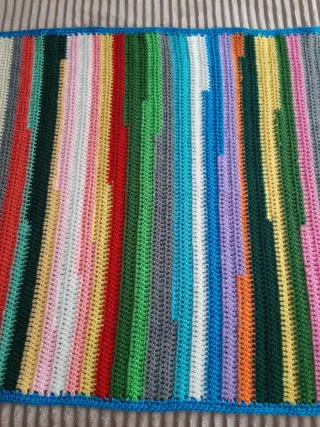 Mantita/alfombra tejida a mano multicolor.