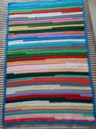 Mantita/alfombra tejida a mano multicolor.