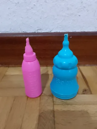 Muñeco bebé con chupete, babero y dos biberones.