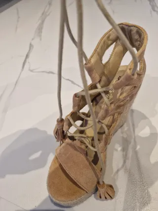 Sandalias cuña ante beige con cordones y flecos.