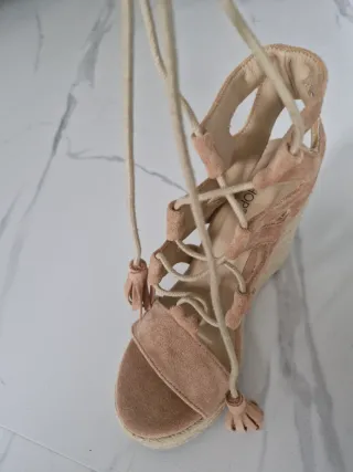 Sandalias cuña ante beige con cordones y flecos.