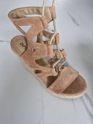 Sandalias cuña ante beige con cordones y flecos.