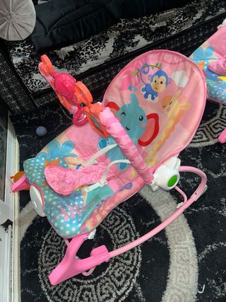 Mecedora de bebé rosa con juguetes