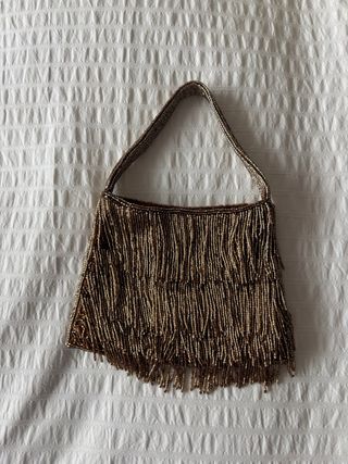 Bolso de mano dorado con flecos de abalorios