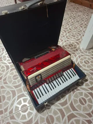 Acordeón rojo, teclas blancas y negras, caja tpte