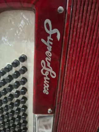 Acordeón rojo, teclas blancas y negras, caja tpte