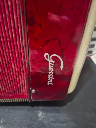 Acordeón rojo, teclas blancas y negras, caja tpte