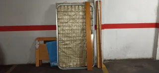 Cama de madera, somier de metal y colchón.