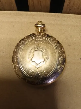 Reloj de bolsillo dorado con moneda