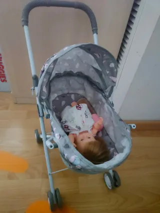 Carrito de muñecas con muñeca y biberón.