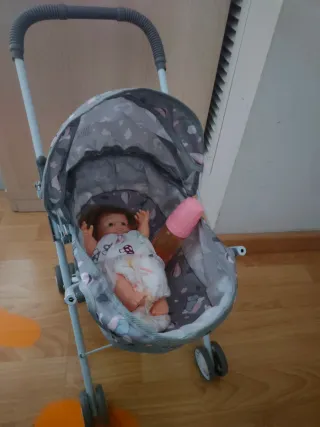 Carrito de muñecas con muñeca y biberón.