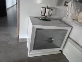 Cómoda blanca con cajones frontales plateados.