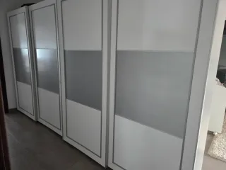 Cómoda blanca con cajones frontales plateados.