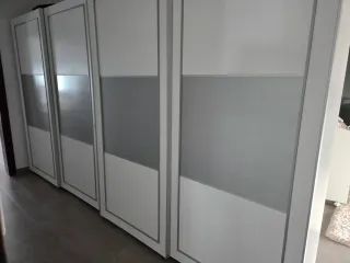 Cómoda blanca con cajones frontales plateados.