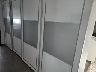 Cómoda blanca con cajones frontales plateados.