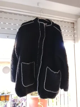 Chaqueta negra con costuras blancas y bufanda.