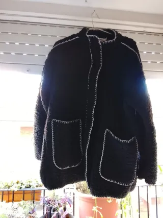 Chaqueta negra con costuras blancas y bufanda.