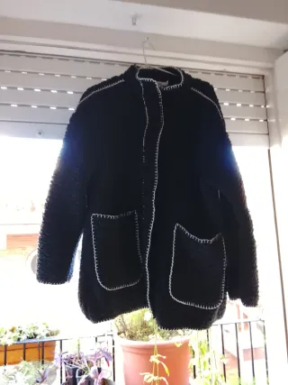 Chaqueta negra con costuras blancas y bufanda.
