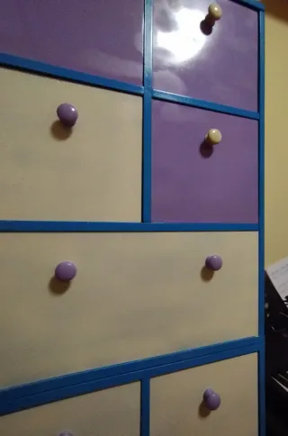 Estantería de madera azul, banca y morada.